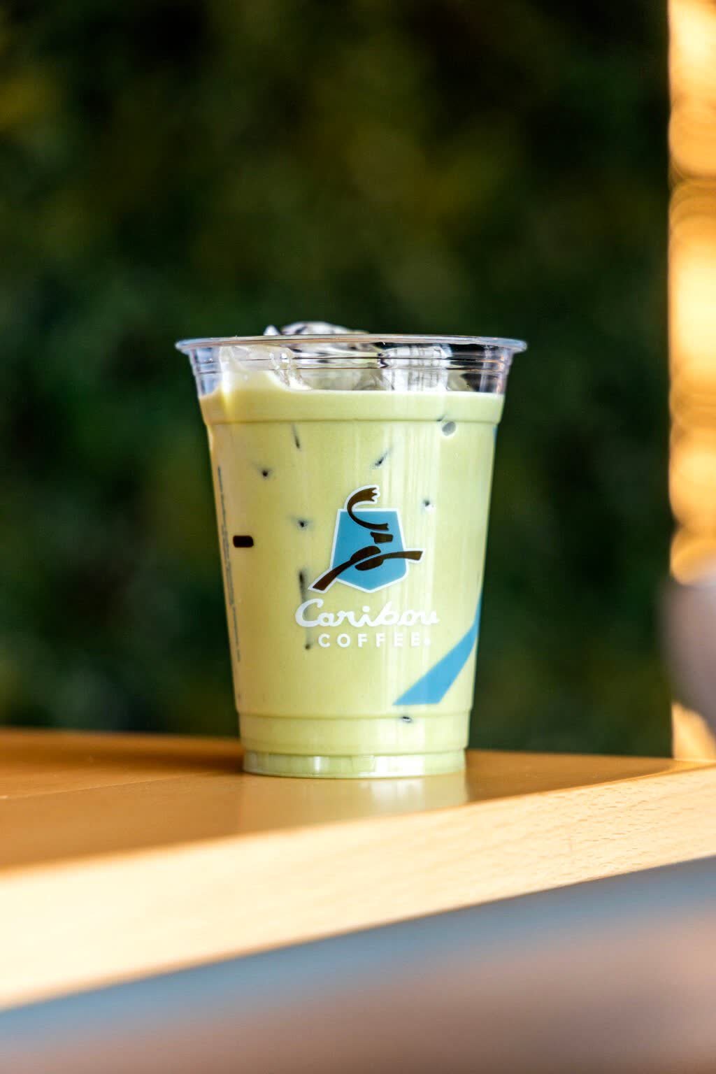 Iced matcha in a branded cup on a wooden ledge, from our Alpro campaign shoot